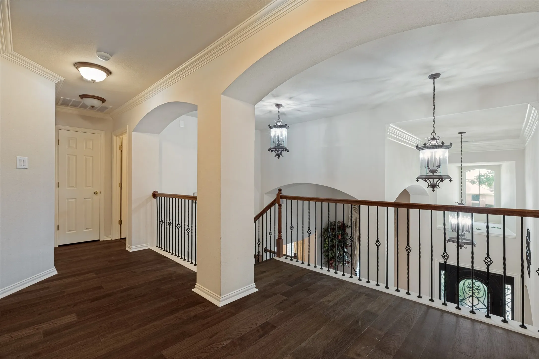 Upper-level hallway featuring rich wood-finish flooring and crown molding