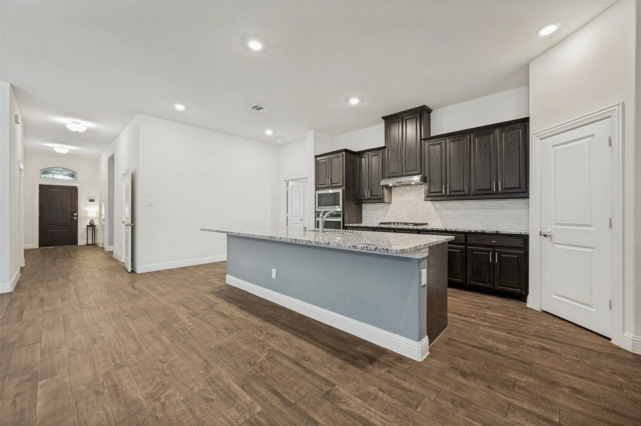 Kitchen island featuring a granite countertop, dark wood-finish cabinetry, and stainless steel appliances