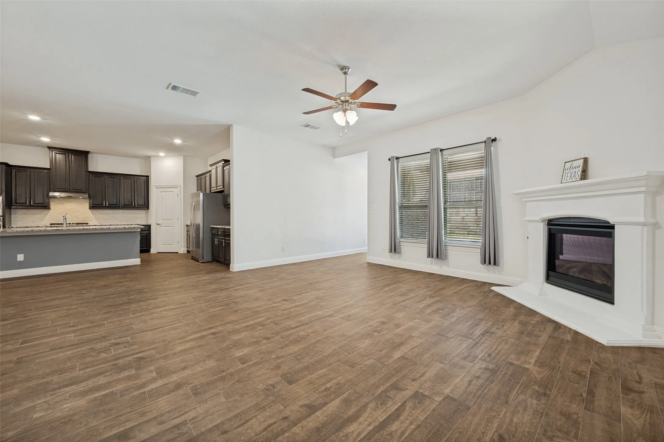 Open-concept living area with wood like-tile & fireplace & view of kitchen