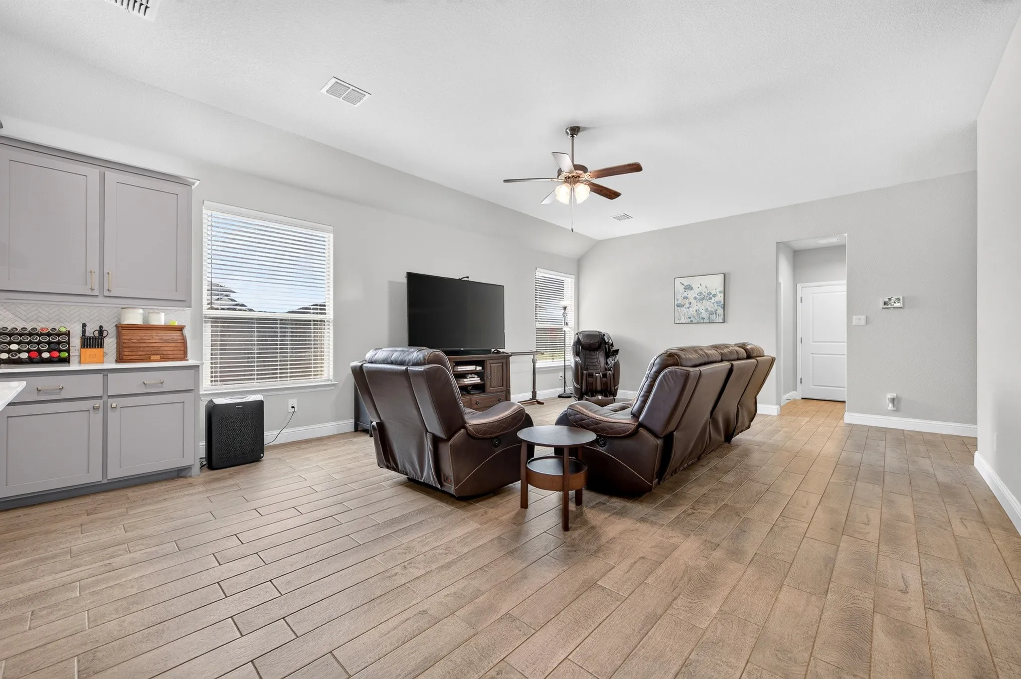 Open-concept living area with wood-finish tile flooring, a vaulted ceiling, and recessed lighting