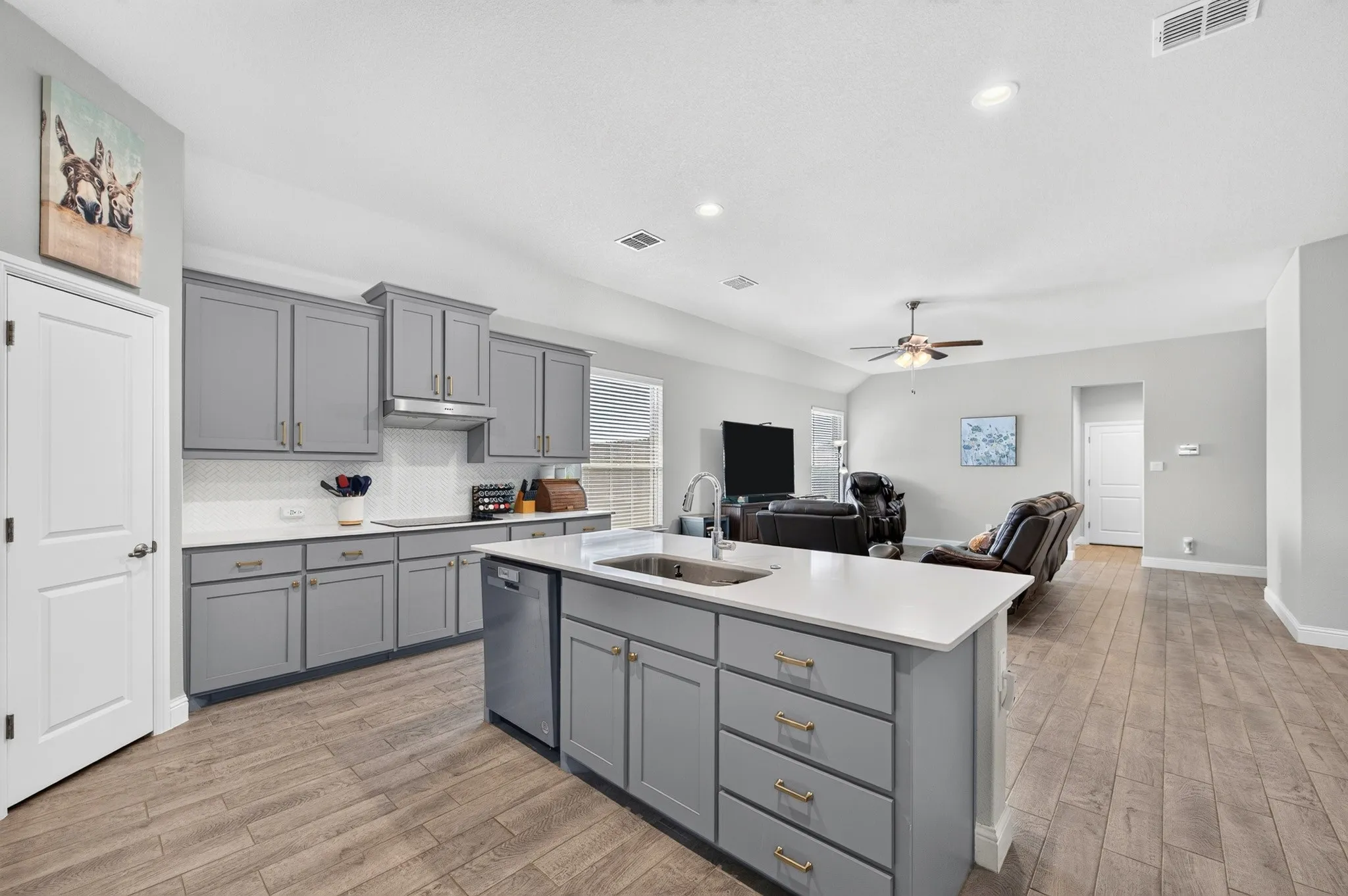 Kitchen featuring gray cabinetry with gold-finish hardware, white countertops, and a white subway tile backsplash