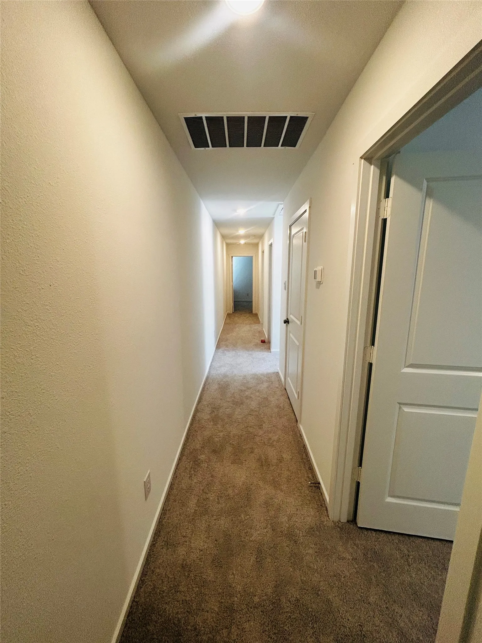 Hallway with neutral carpeting, white walls, and recessed lighting