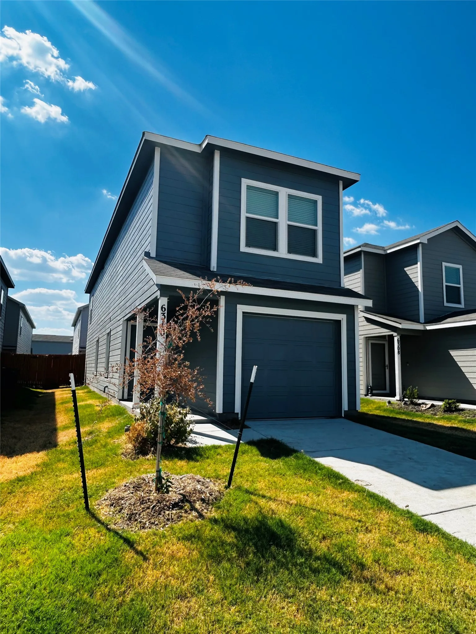Two-story residence featuring a dark blue siding exterior, a single-car garage, and white trim accents