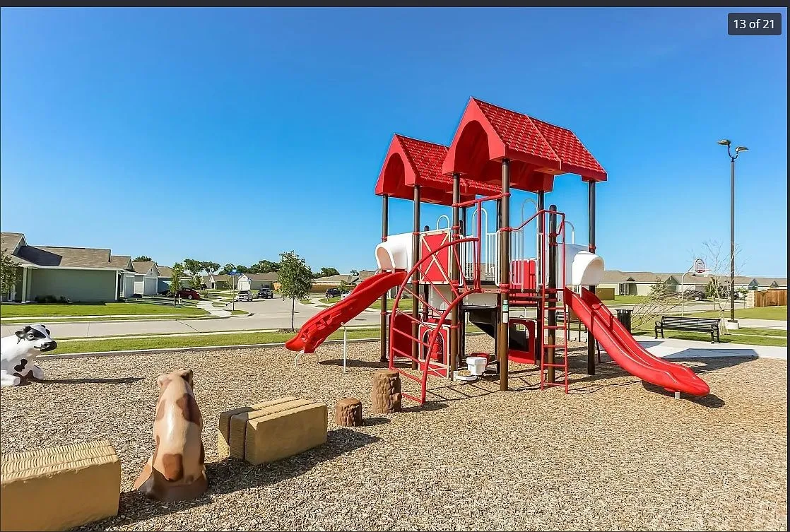 Community playground featuring a multi-level play structure with multiple slides, red roofing, and climbing elements