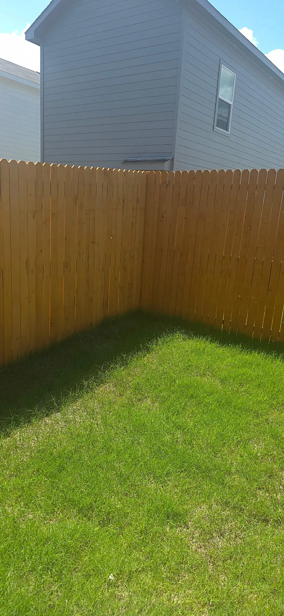 Private backyard space featuring a wood picket fence and a grass lawn