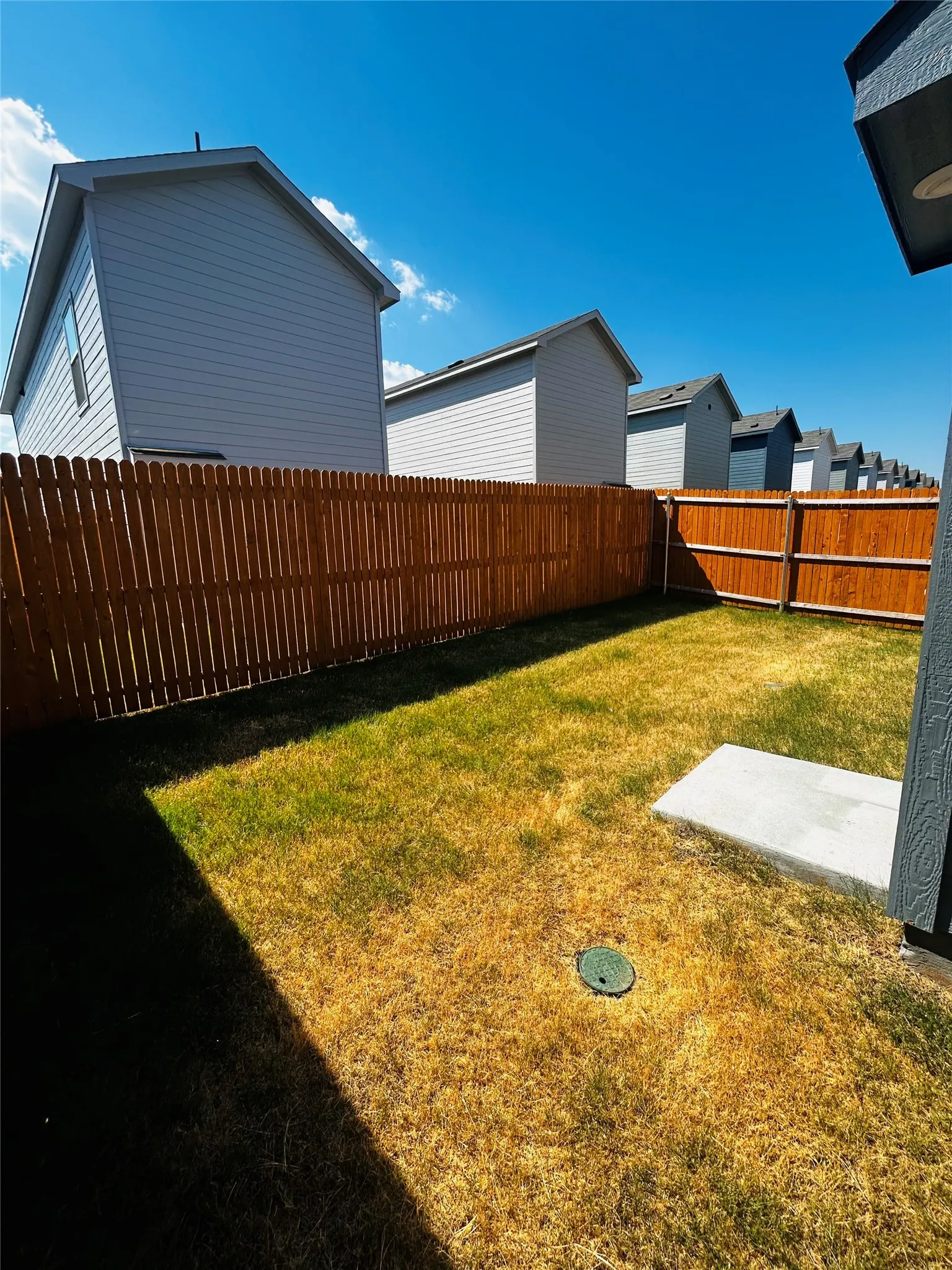 Private backyard with wood fencing and a concrete pad