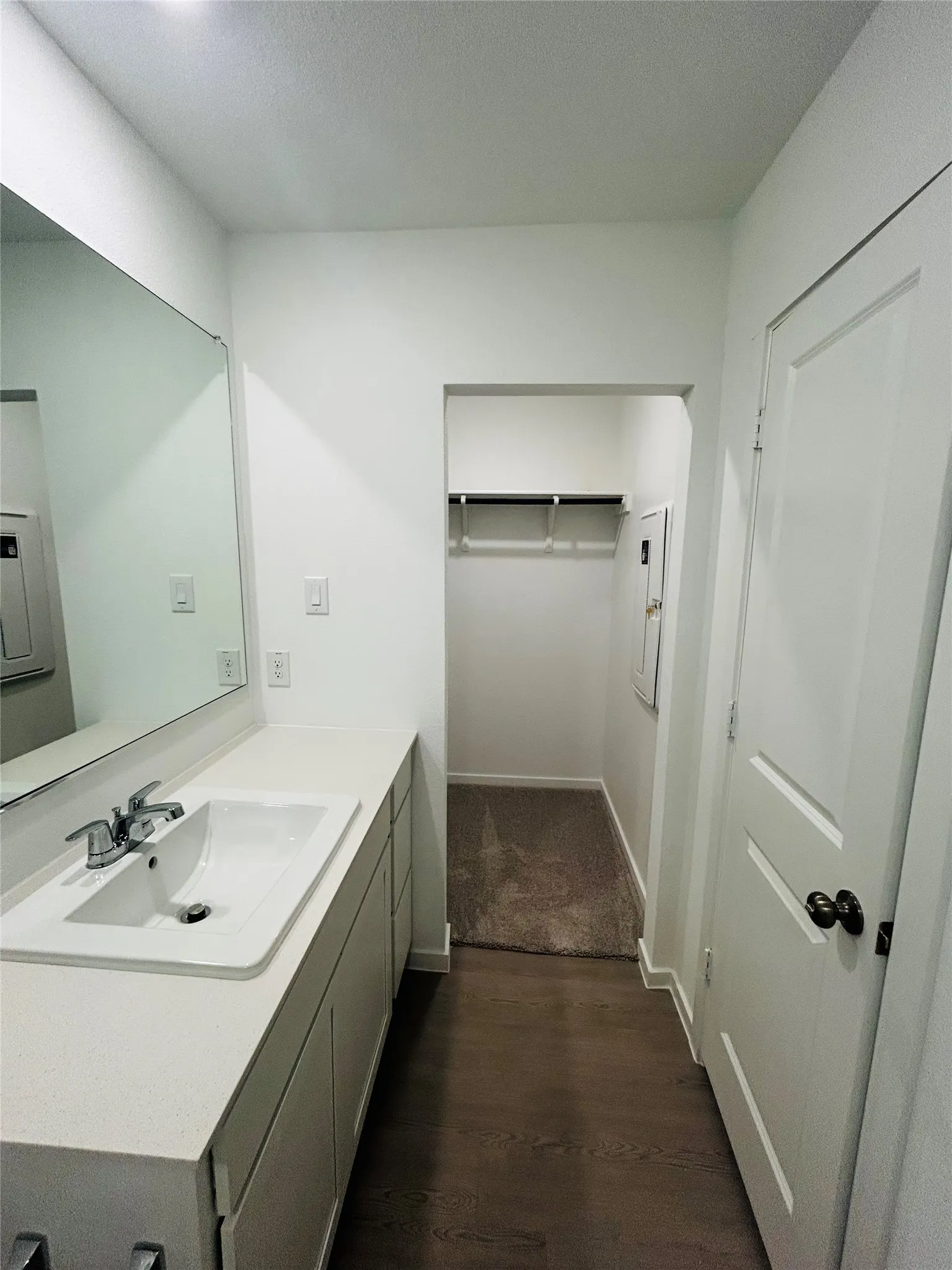 Vanity with integrated sink, chrome faucet, and expansive wall mirror