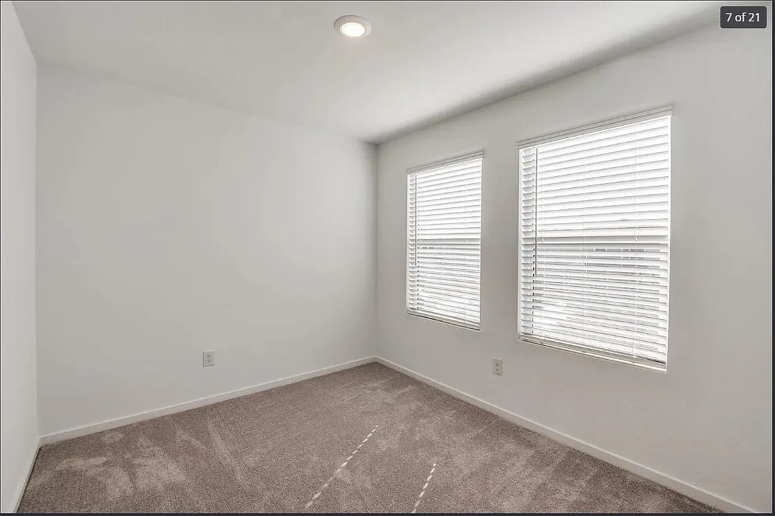 Room featuring two windows with blinds, recessed lighting, white walls, and neutral-toned carpeting