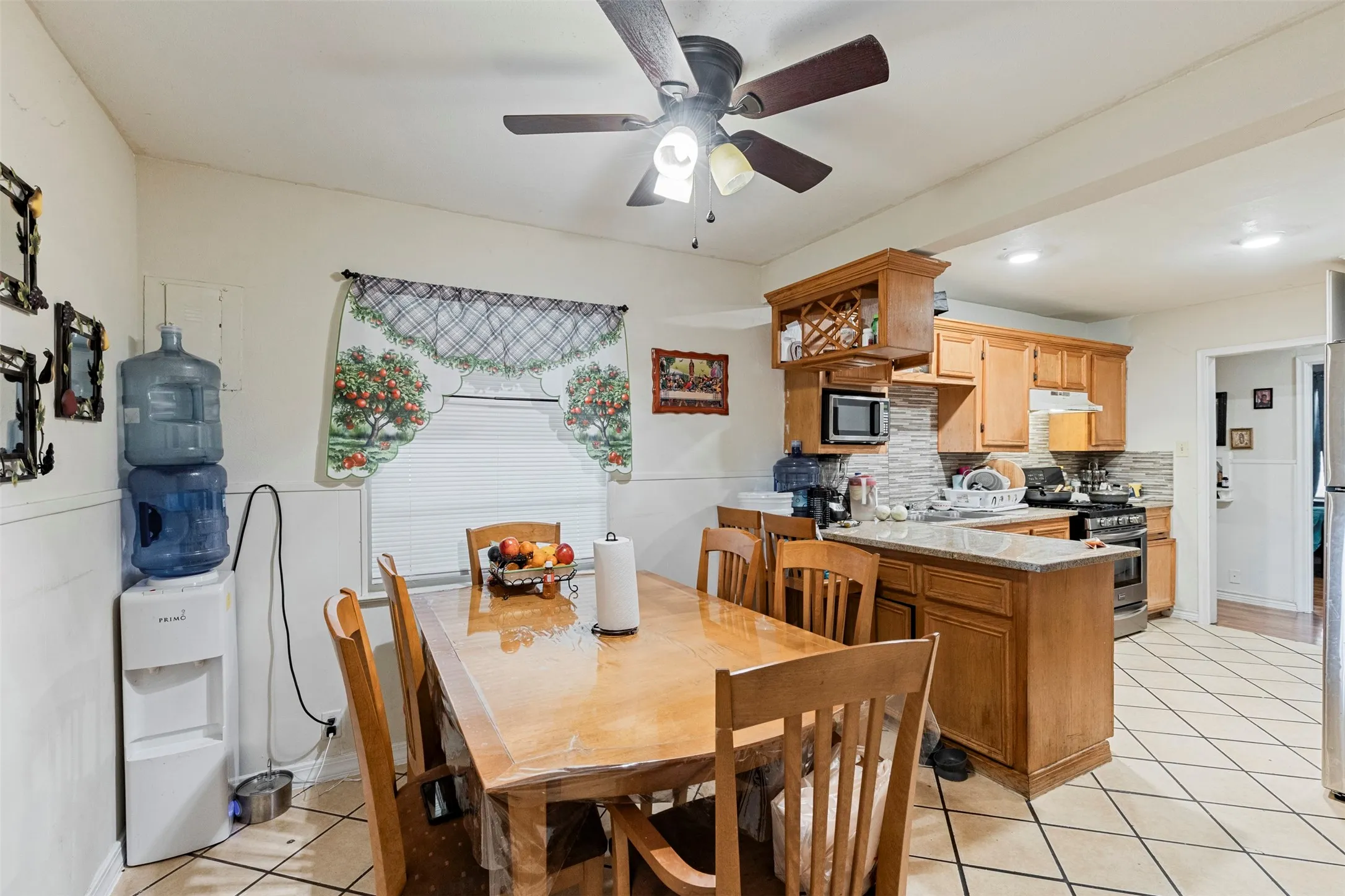 Kitchen area featuring light wood cabinetry, a tiled backsplash, and granite-finish countertops