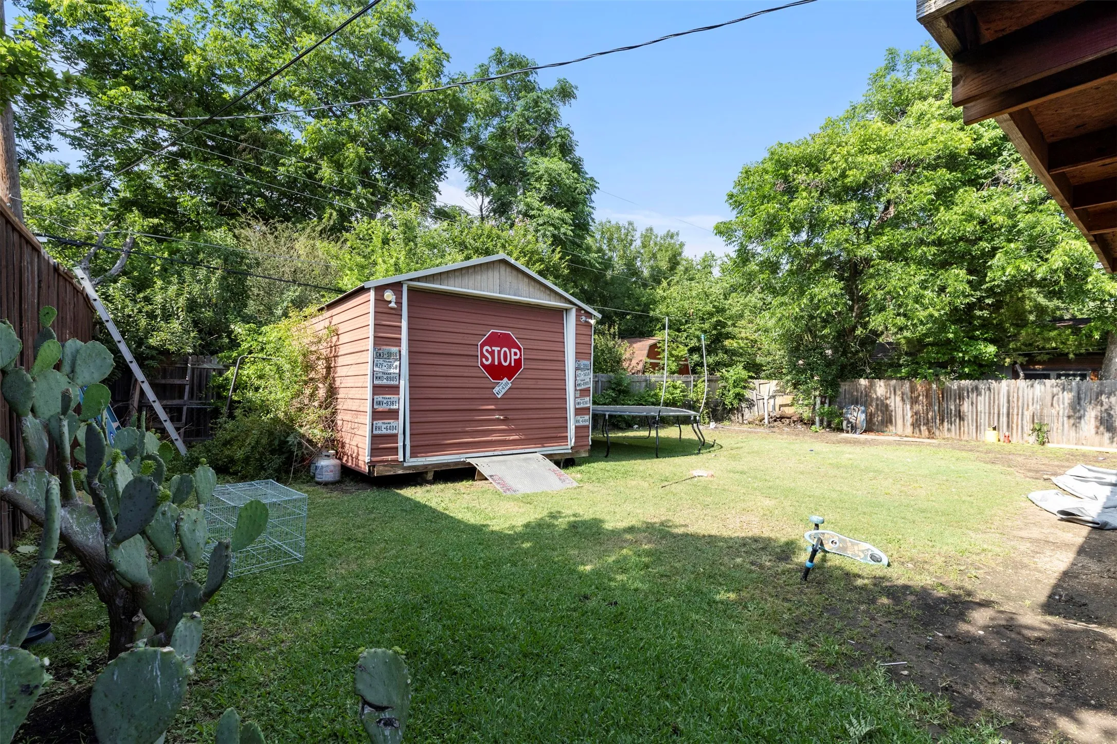 Expansive backyard featuring a central lawn, mature perimeter trees, and a wooden privacy fence