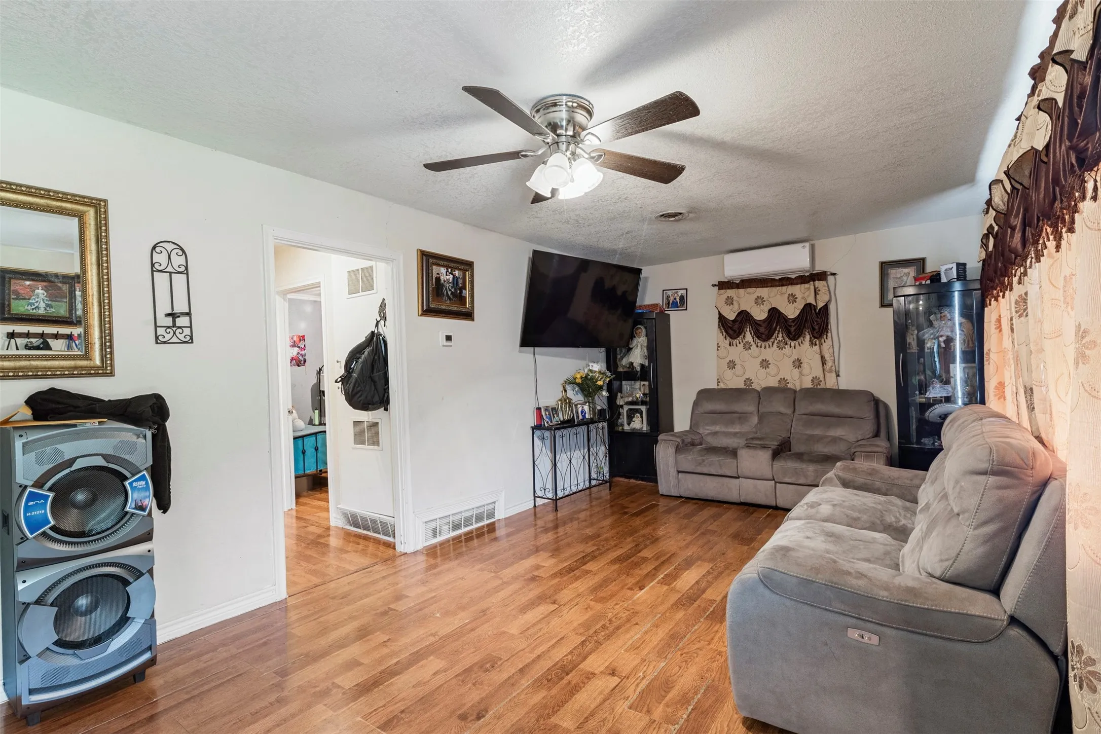 Living area featuring wood-finish flooring, a ceiling fan, and white walls