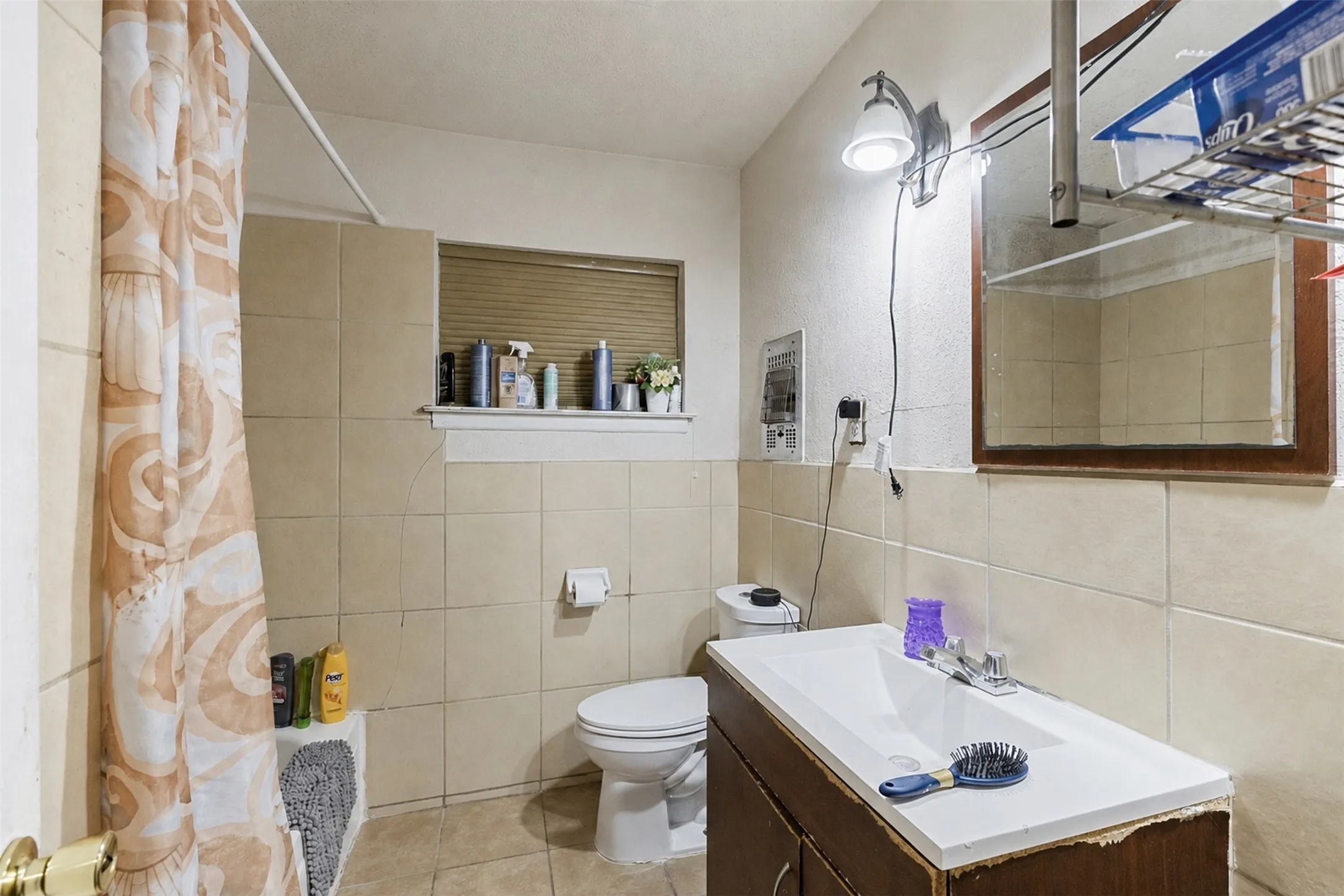 Bathroom featuring a vanity with an integrated sink, a toilet, and a tiled shower area