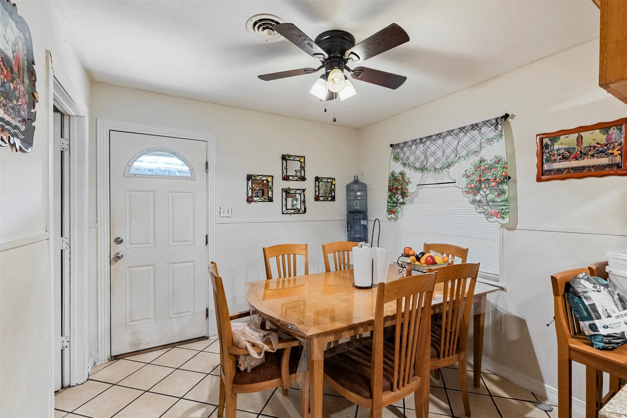 White paneled door with an arched window, tile flooring, and a ceiling fan with light fixture