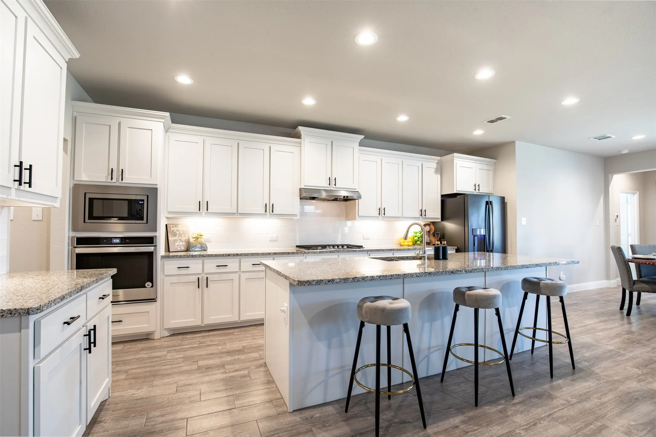 White kitchen with recessed lighting and large island.