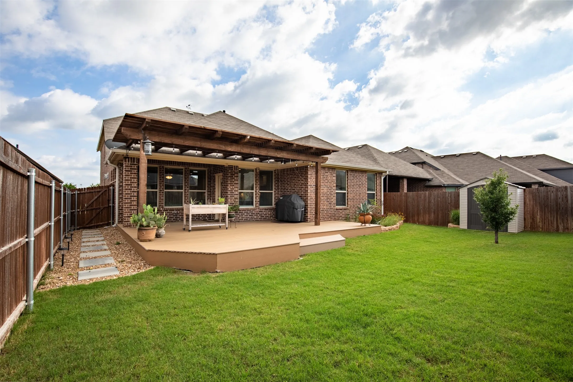 Large yard, upgraded with pergola and deck. Great stepping stones to access the backyard through the front gate.
