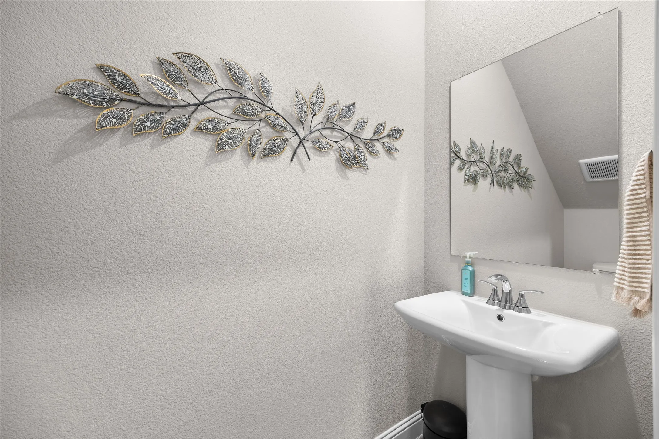 This convenient powder bath was a chosen owner upgrade, featuring a stylish pedestal sink and a framed mirror. This thoughtfully placed half-bath is perfect for guests and adds excellent functionality to the home's layout.