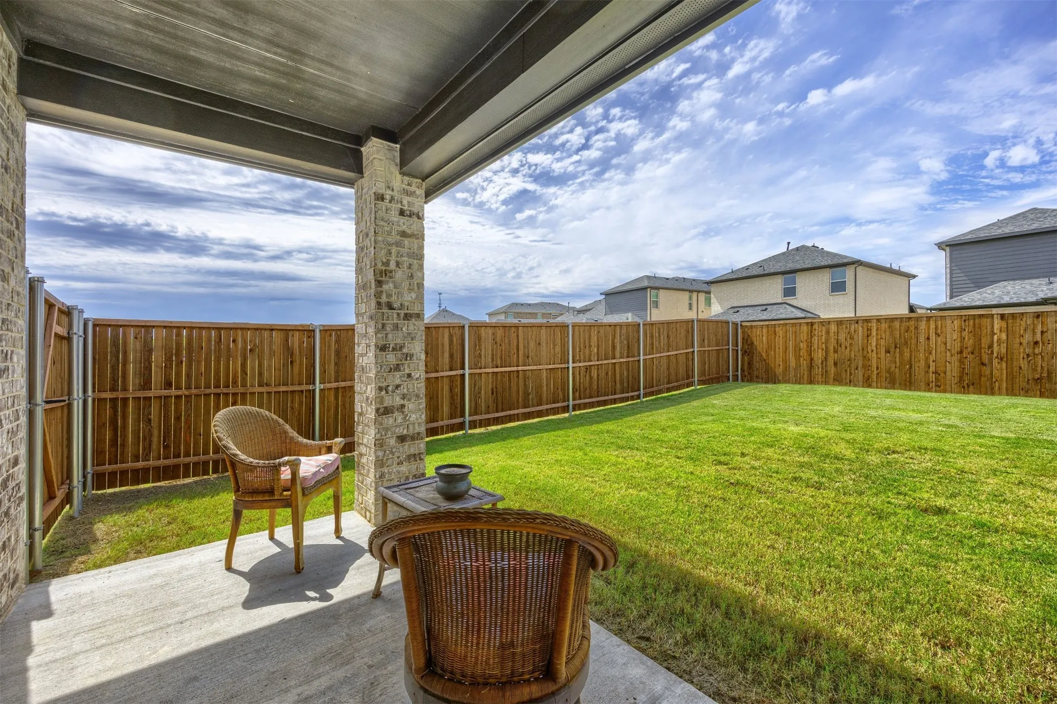 Covered patio featuring concrete flooring and brick support columns