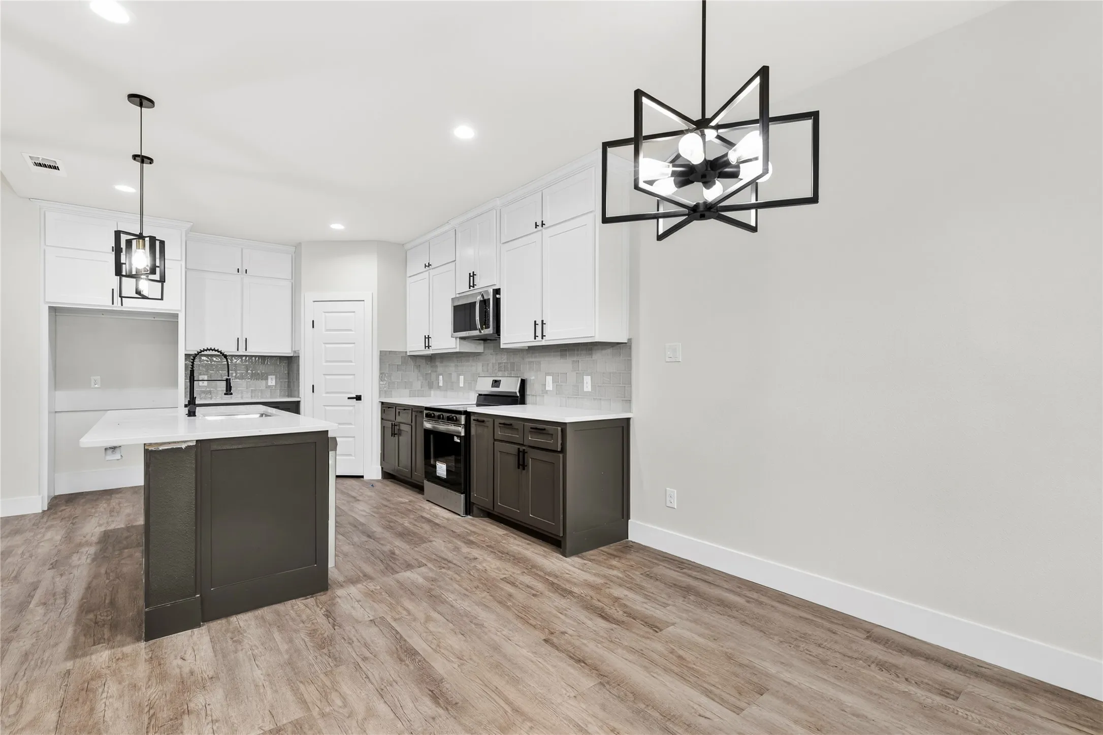 Modern kitchen featuring a central island with an undermount sink, white countertops, and wood-finish flooring