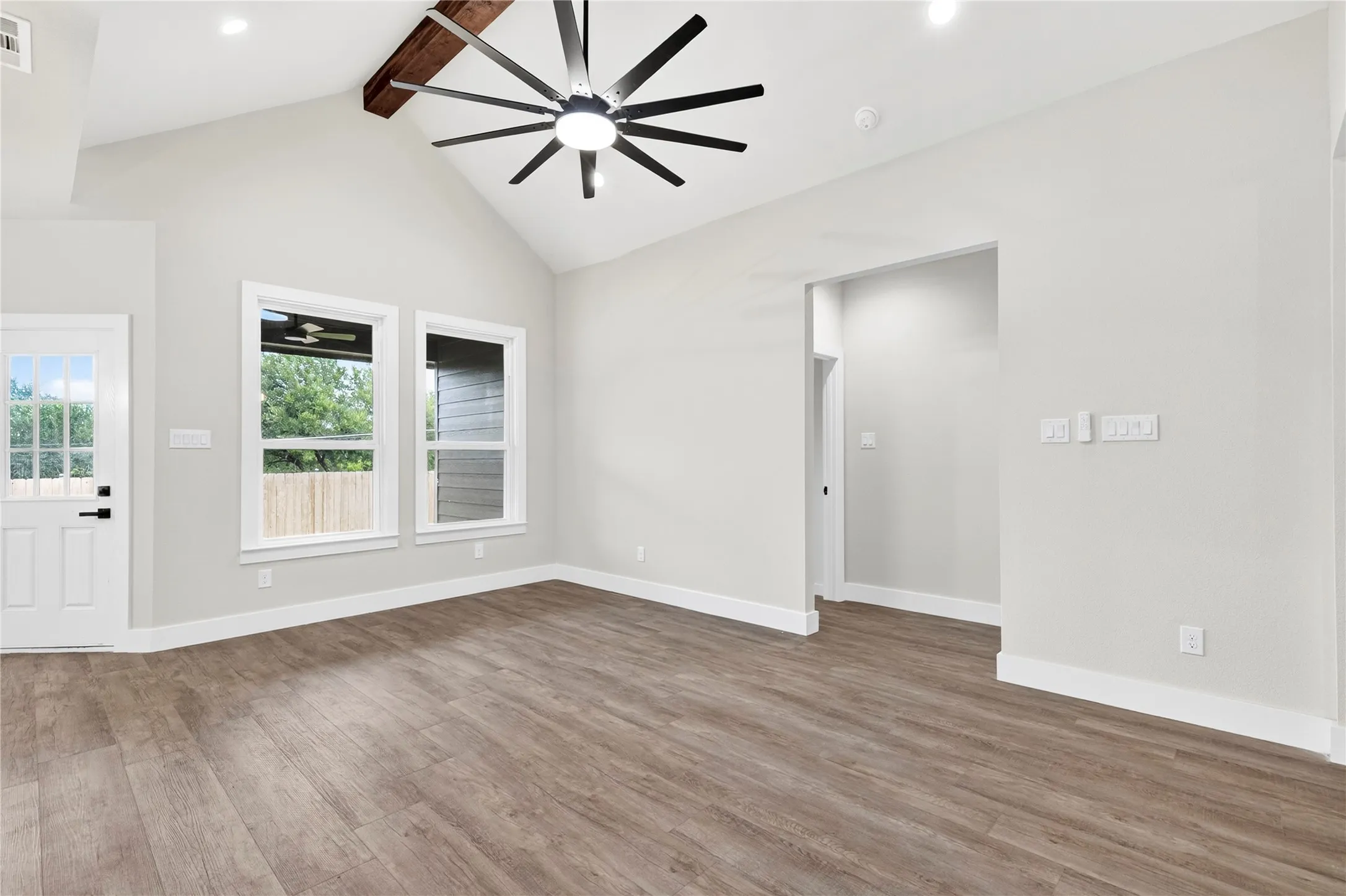 Vaulted ceiling with exposed wood beam and a large ceiling fan