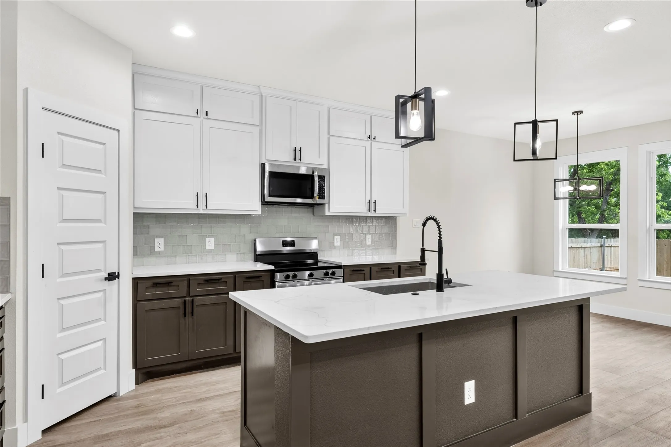 Contemporary kitchen featuring a large island with an undermount sink, a gooseneck faucet, and pendant lighting