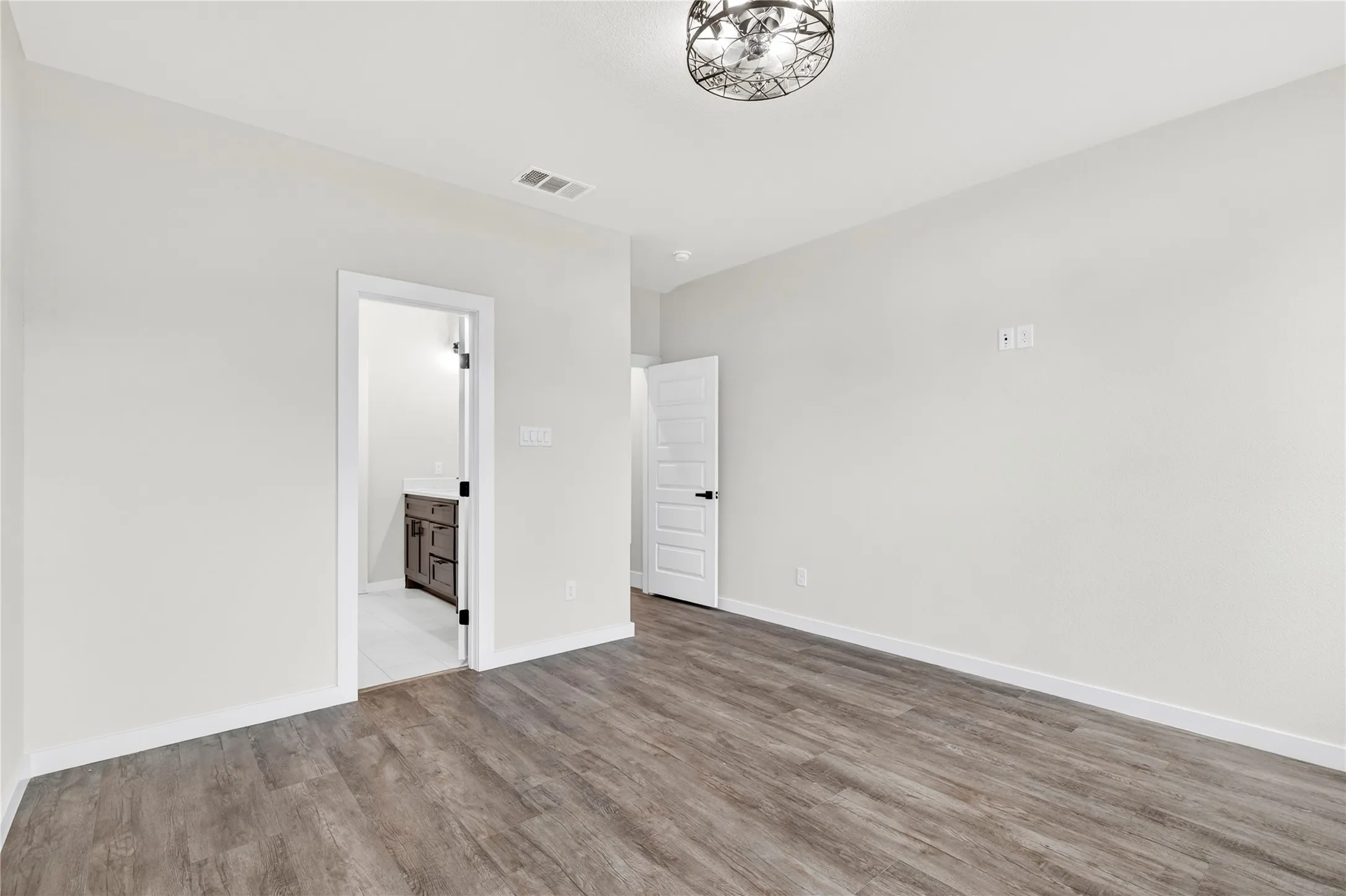 Spacious room featuring wood-finish flooring, light-colored walls, and crisp white trim