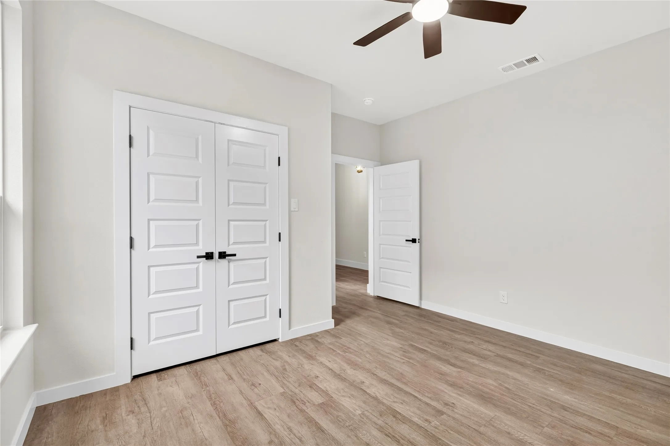 Interior room featuring wood-finish flooring, white baseboards, and light neutral wall finishes