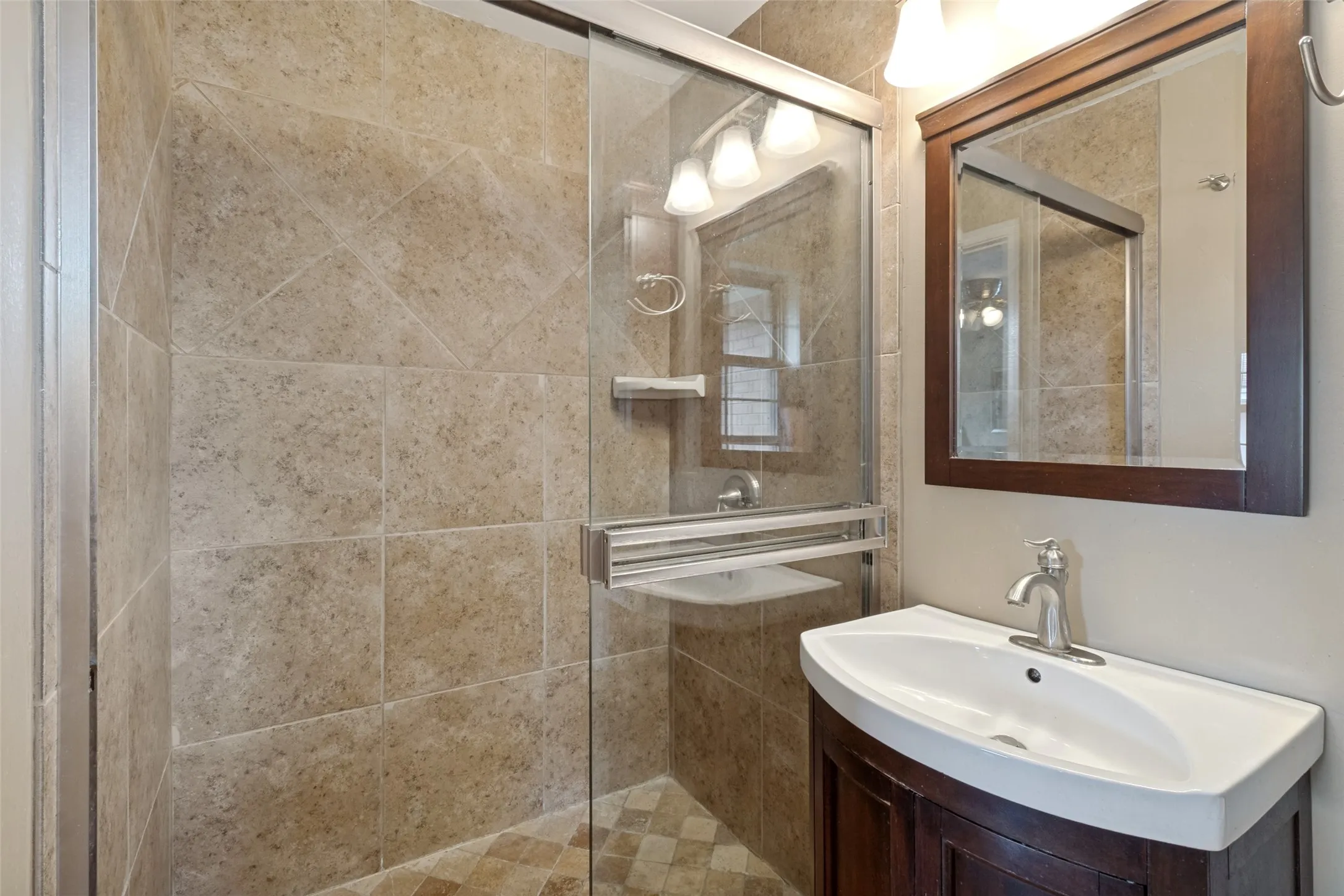 Glass-enclosed shower with full tile surround and tiled flooring
