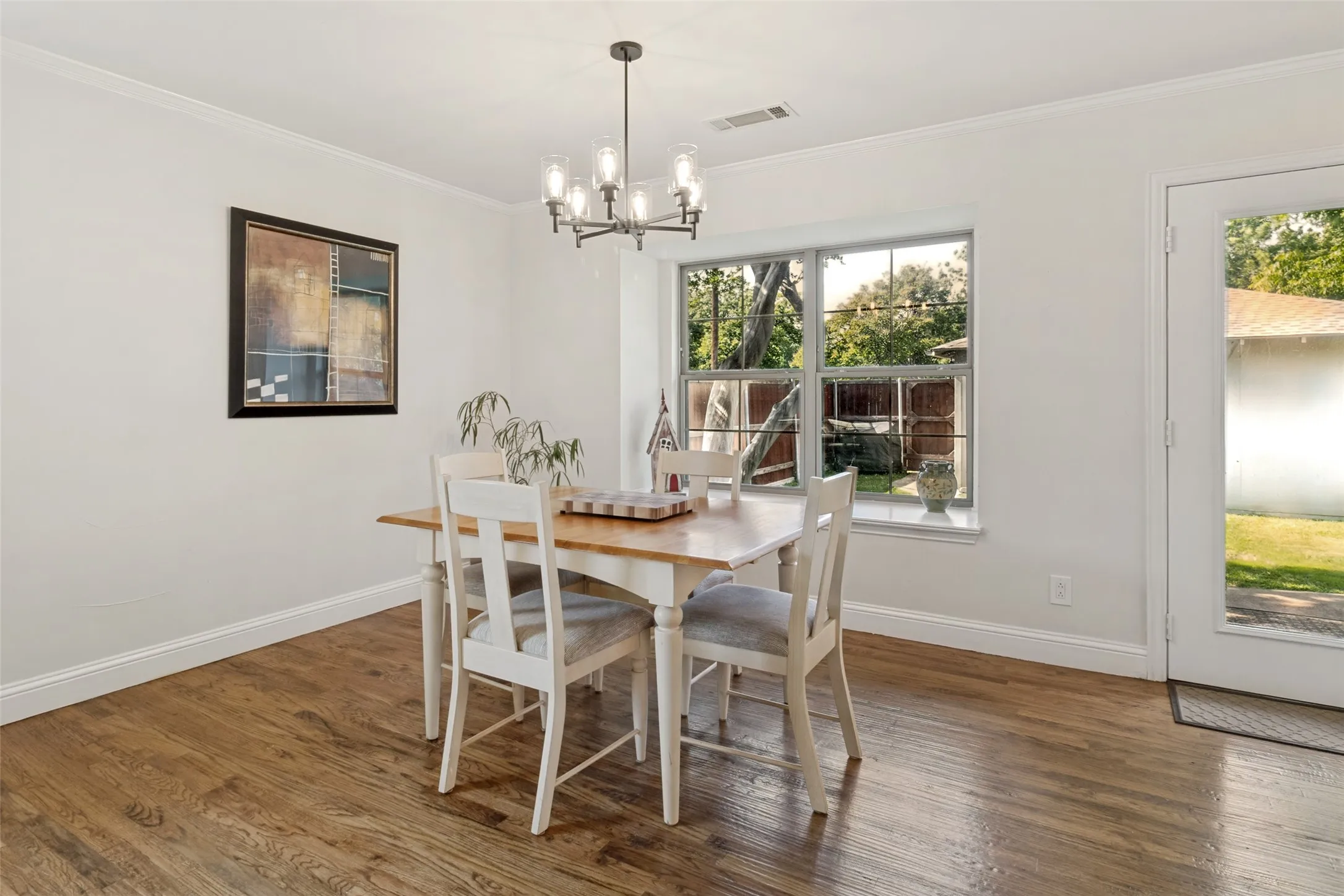 Dining area featuring wood flooring, a contemporary chandelier, a large window, a glass-paneled door