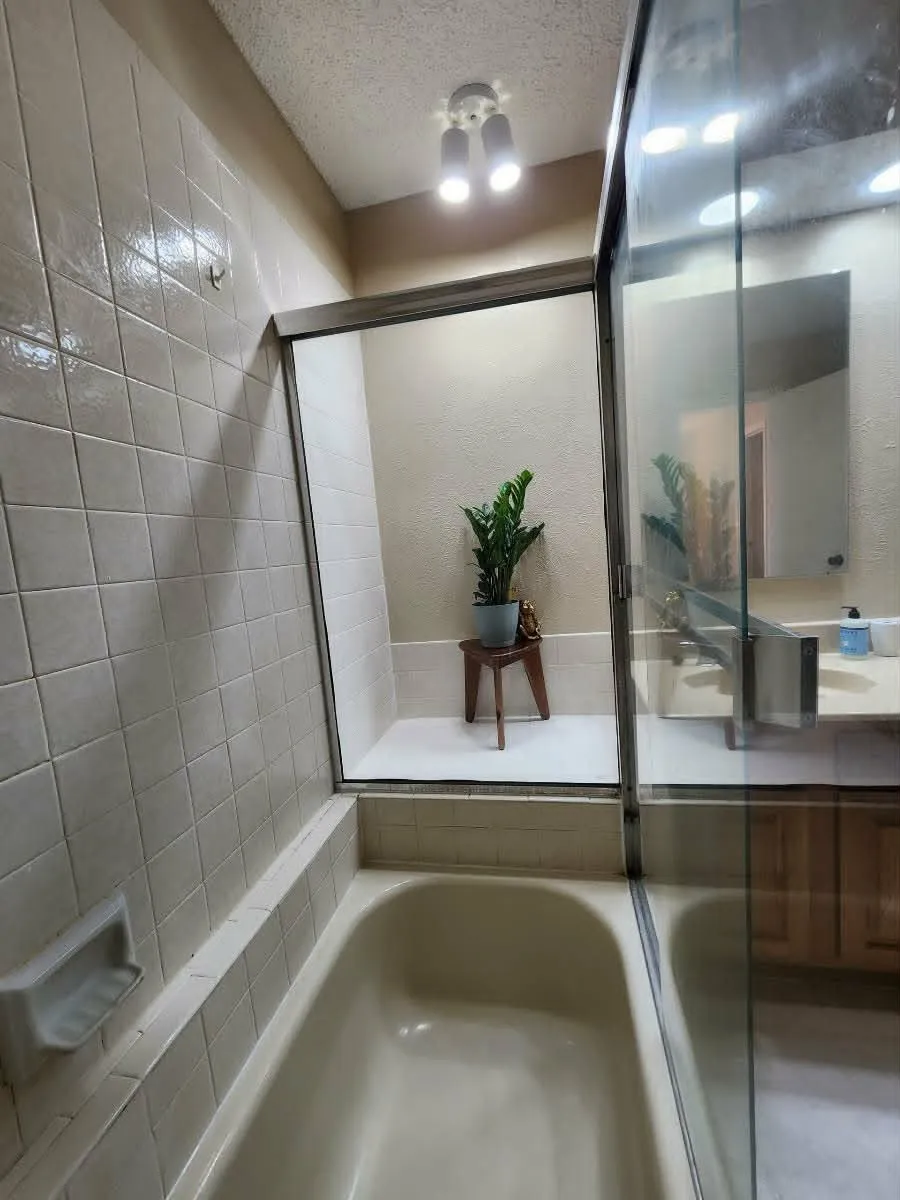 Bathroom featuring a built-in bathtub with tiled surround and glass sliding shower doors