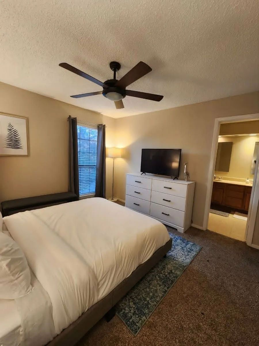 Bedroom featuring a ceiling fan, window with blinds, and carpet flooring