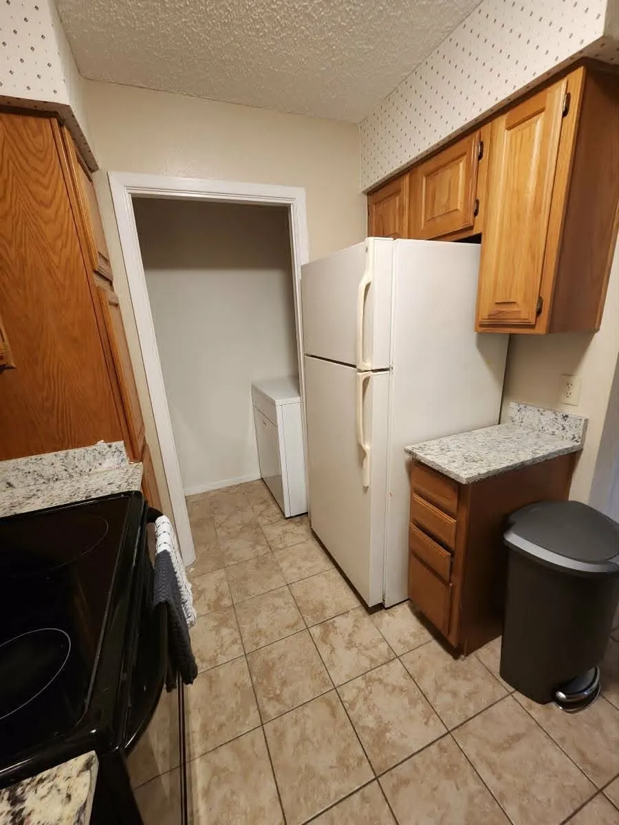 Kitchen area featuring light wood cabinetry, stone-look countertops, and neutral-toned tile flooring