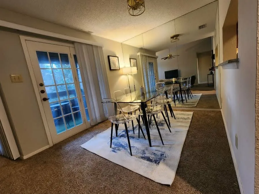 Dining area featuring full-wall mirroring, a contemporary ceiling light fixture, and plush carpeting