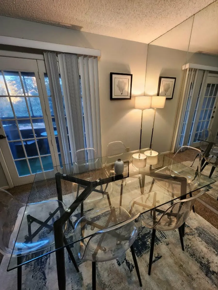 Dining area featuring dual glass-paned French doors with vertical blinds, a full-wall mirror, and textured ceilings
