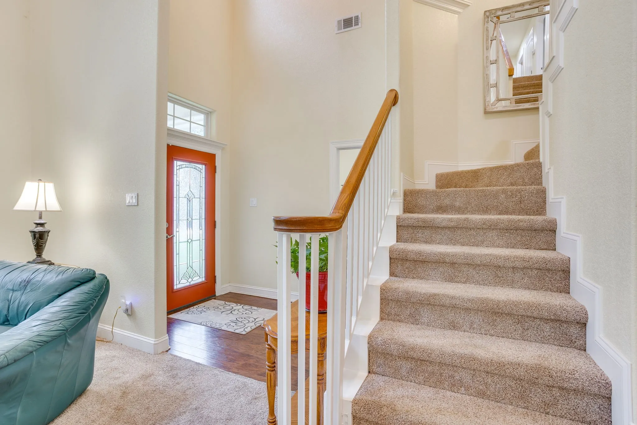 Carpeted staircase with white balusters and a wood handrail