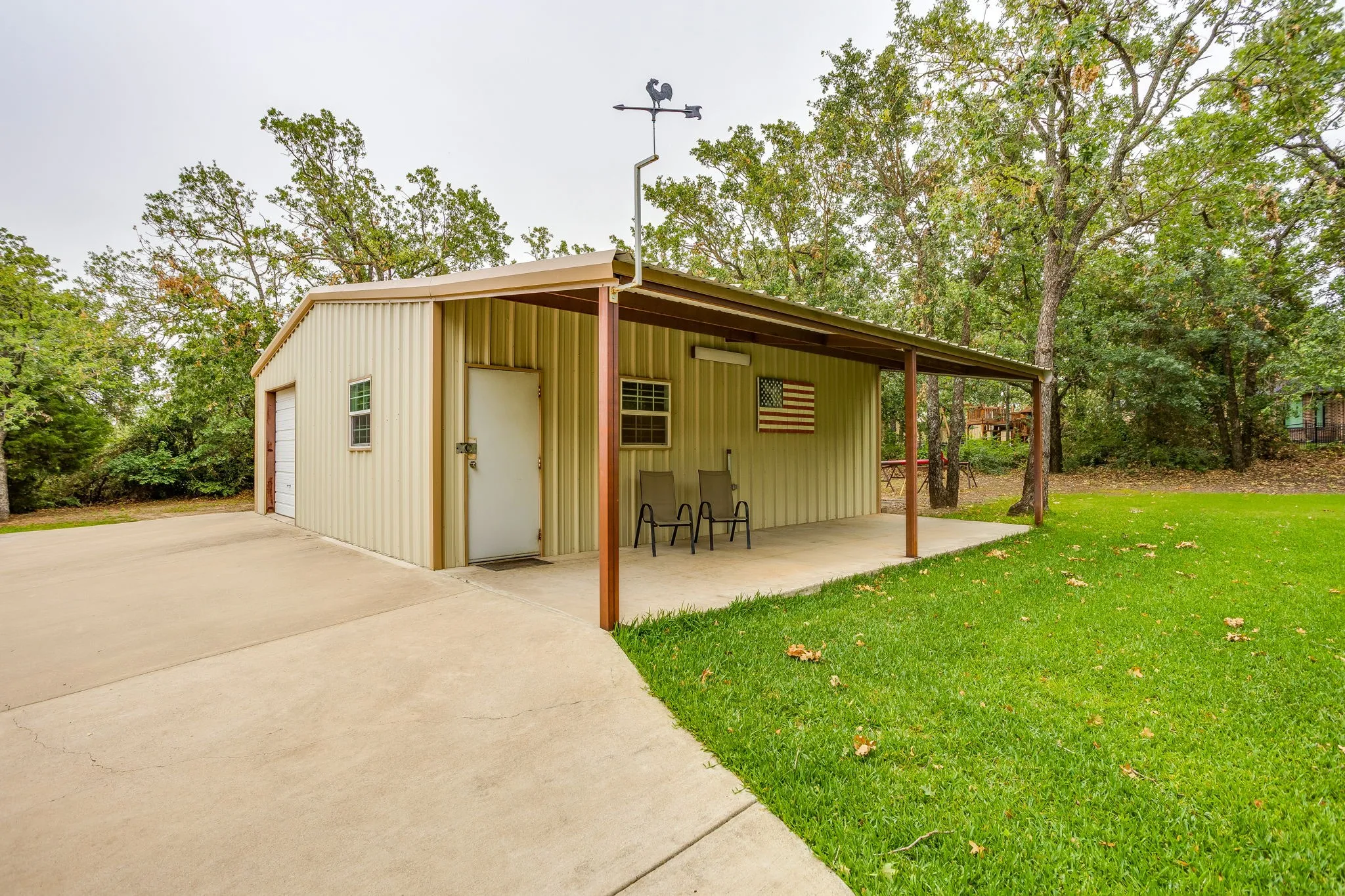 Metal outbuilding featuring a single garage door, a side entry door, and a covered patio area