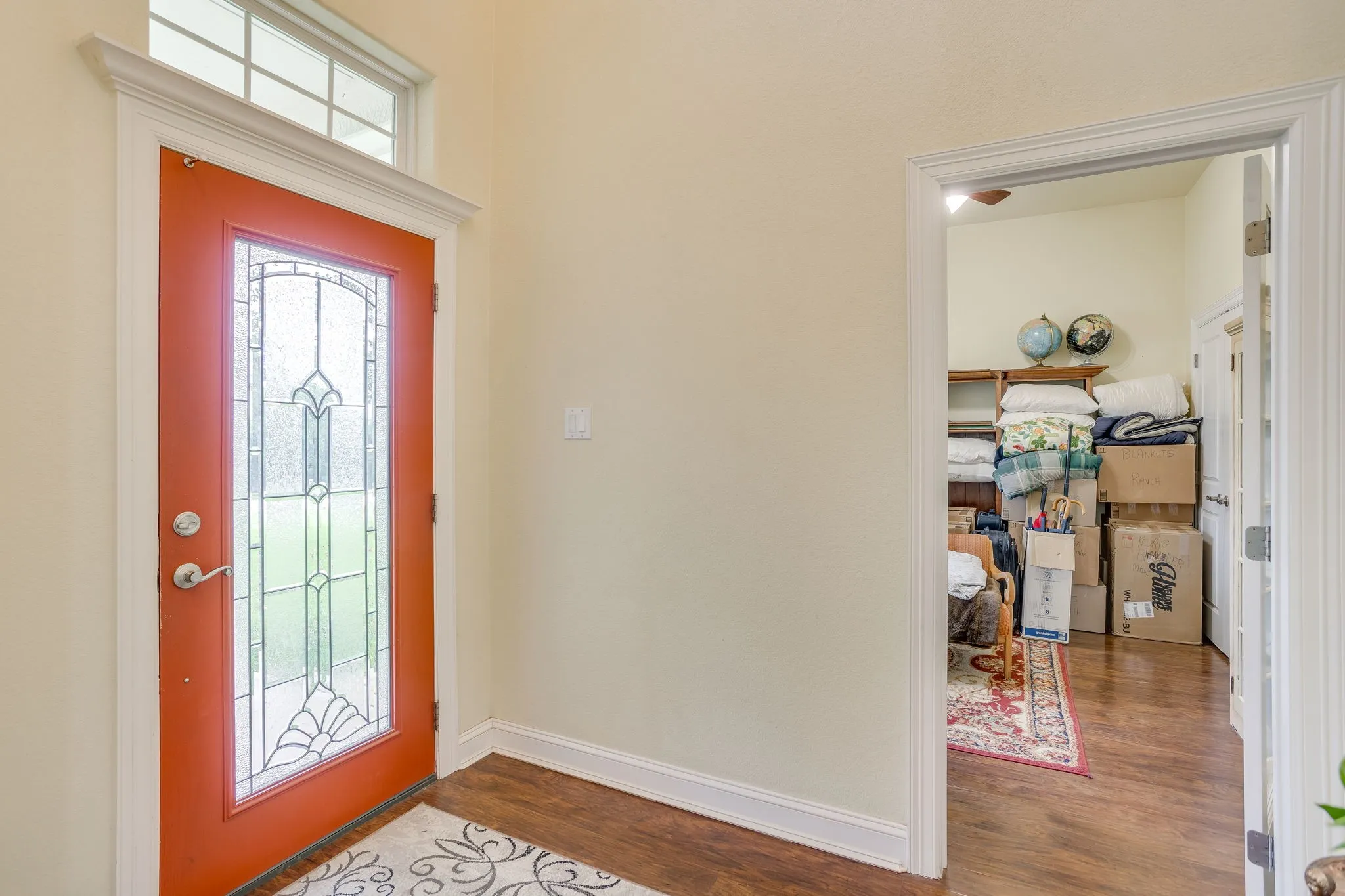 Entryway featuring a red front door with decorative leaded glass, an overhead transom window, and white trim