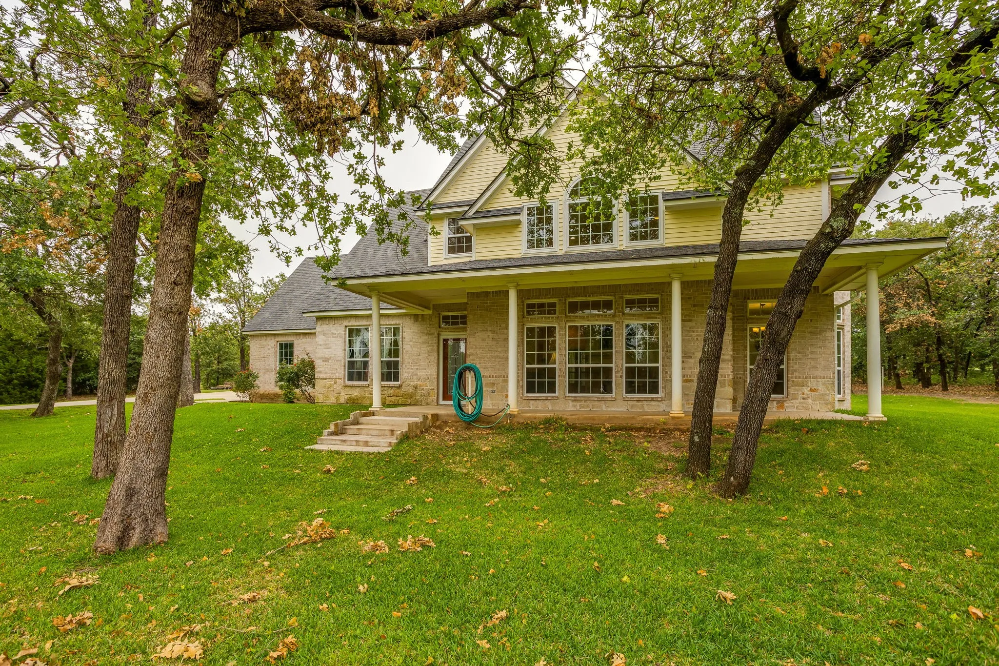 Stone and siding exterior with a covered porch and column details