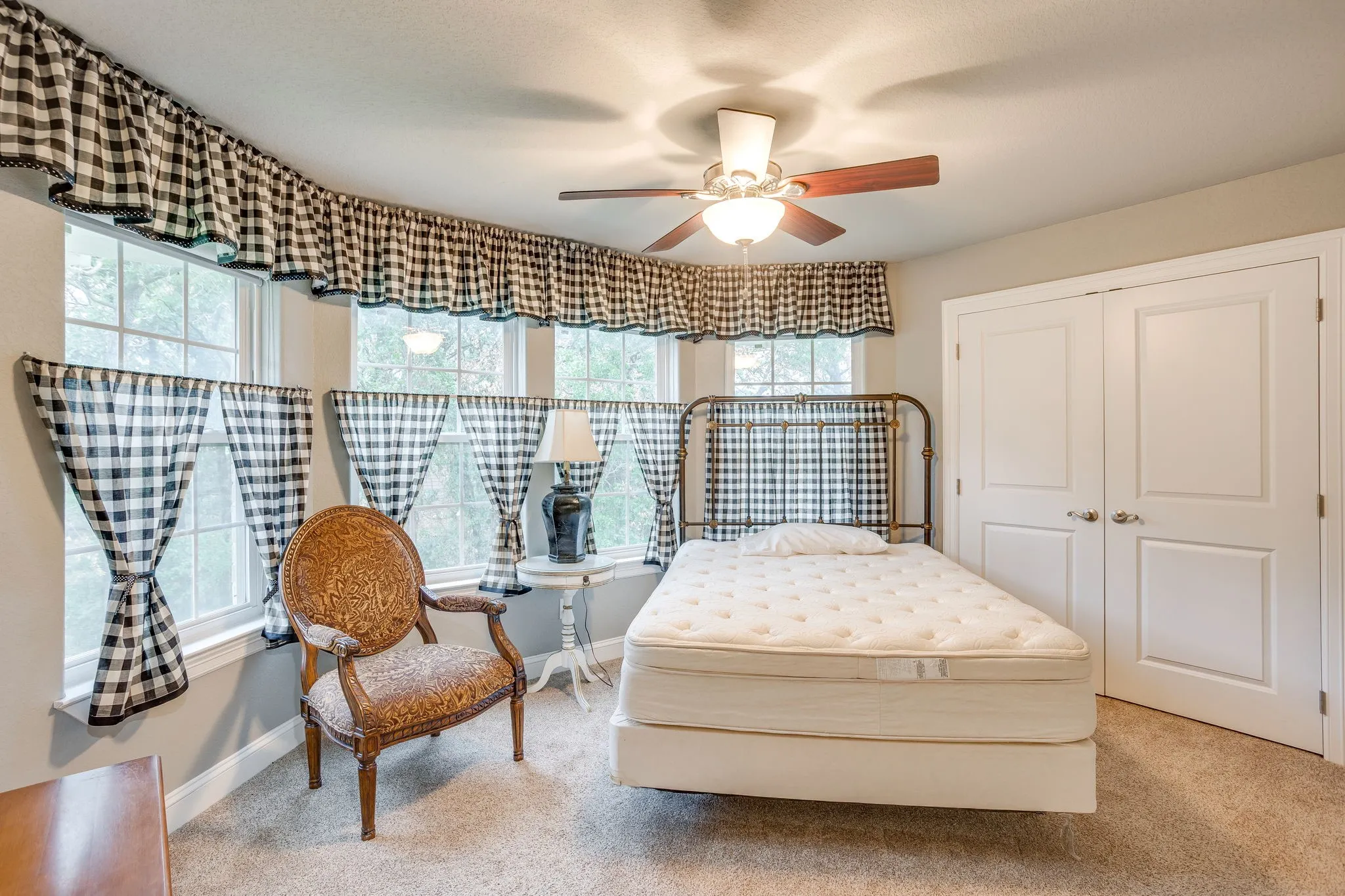 Carpeted room featuring multiple windows with trim, a ceiling fan with light fixture, and double bi-fold closet​​‌​​​​‌​​‌‌​‌‌​​​‌‌​‌​‌​‌​​​‌​​ doors