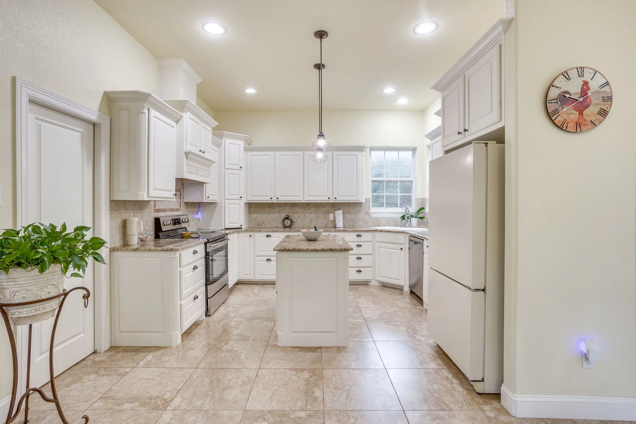 Kitchen featuring white cabinetry, a central island with pendant lighting, stone countertops, and tile flooring