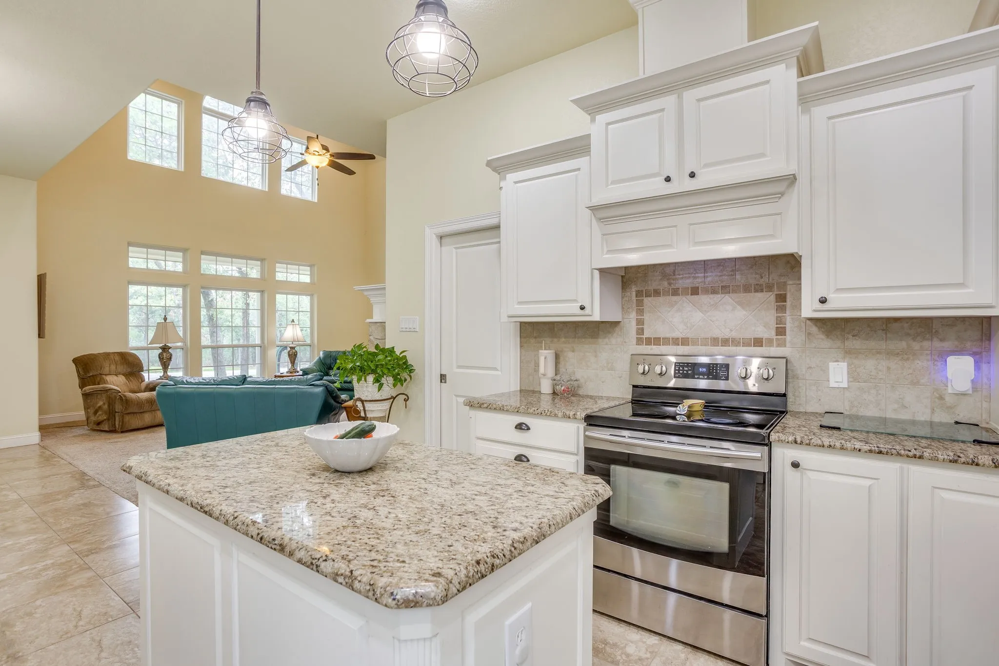 Bright kitchen featuring white cabinetry, granite countertops, tile flooring, and stainless steel appliances