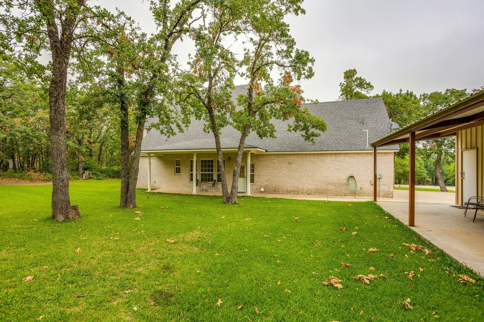 Expansive green lawn with mature trees and a covered patio area
