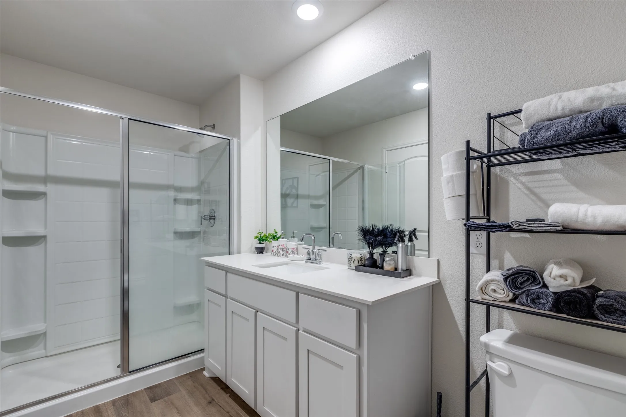 Bathroom with wood finished floors, vanity, a stall shower, and a textured wall