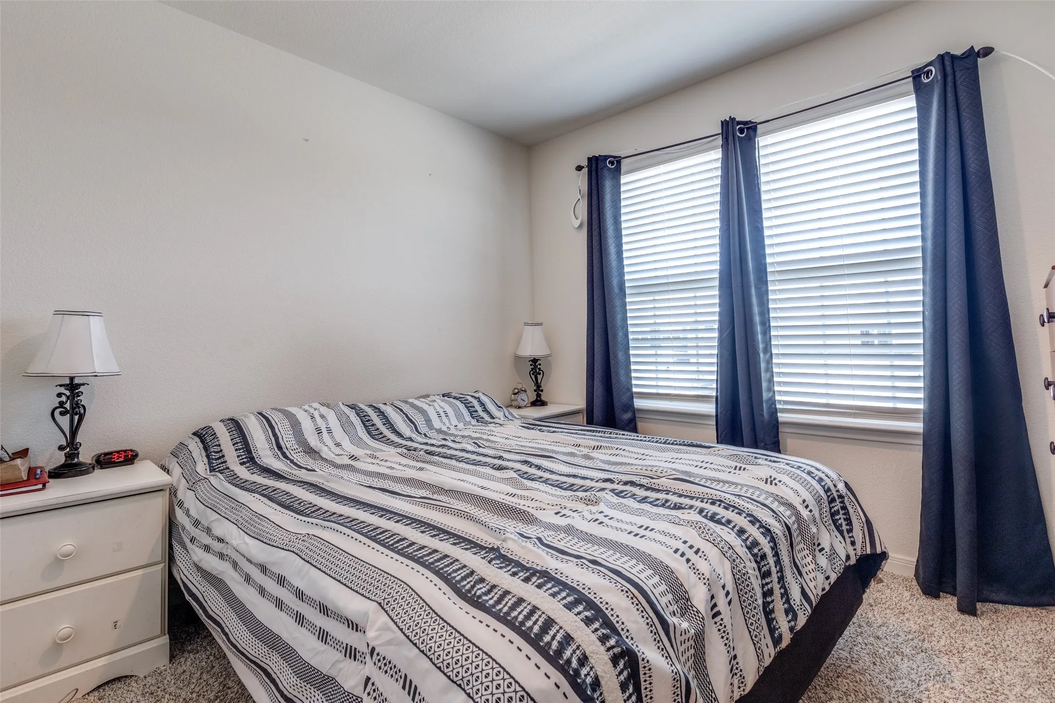 Bedroom with light carpet and multiple windows