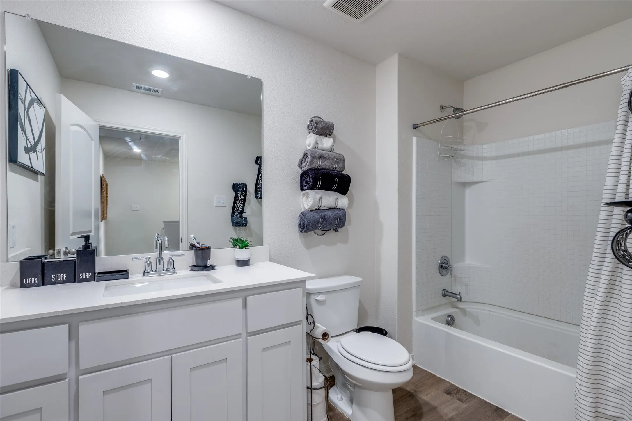 Full bath with wood finished floors, vanity, and washtub / shower combination