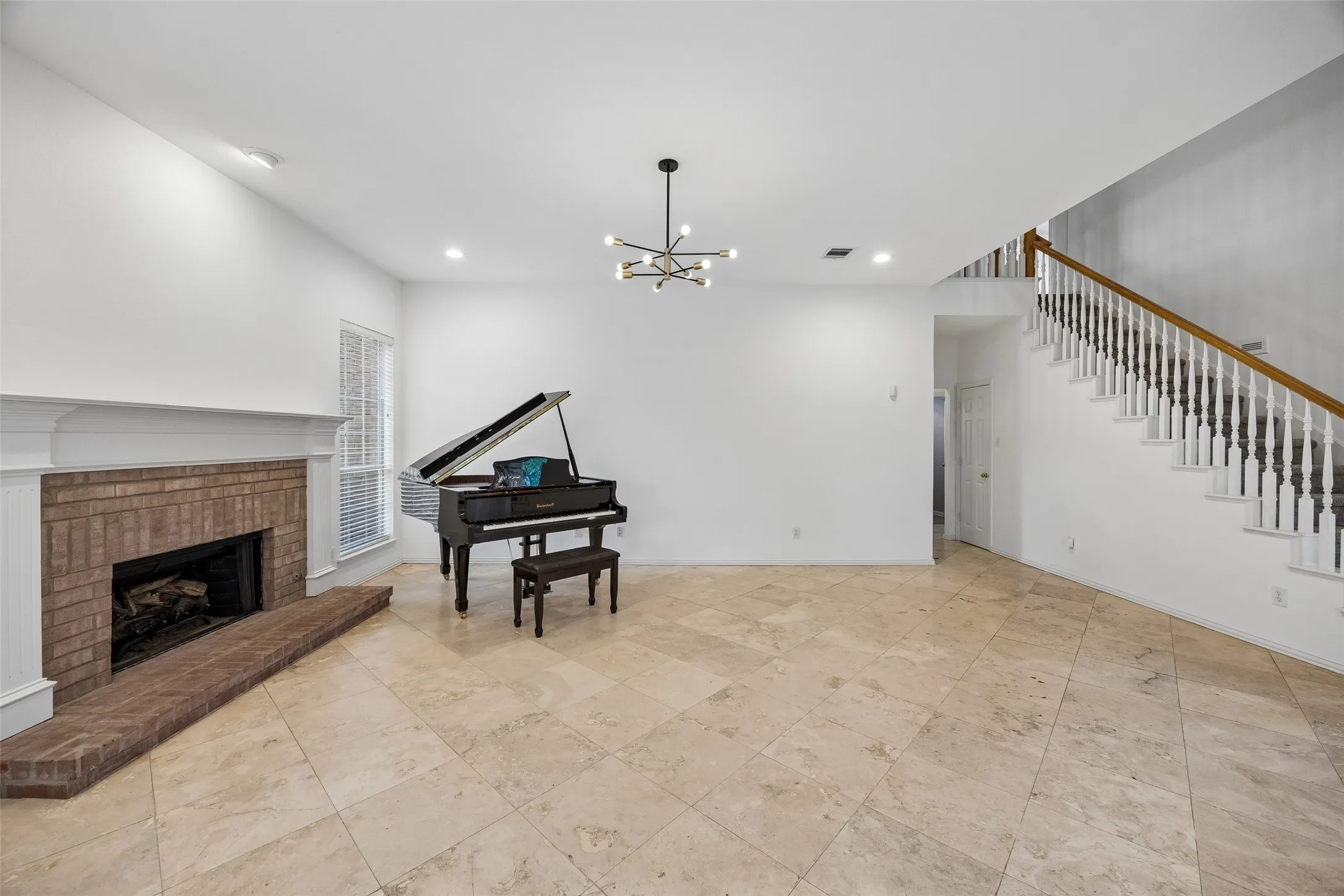 Spacious open-concept living area featuring a fireplace with a brick surround, white mantle, multiple windows, and a built-in breakfast bar with a dark countertop