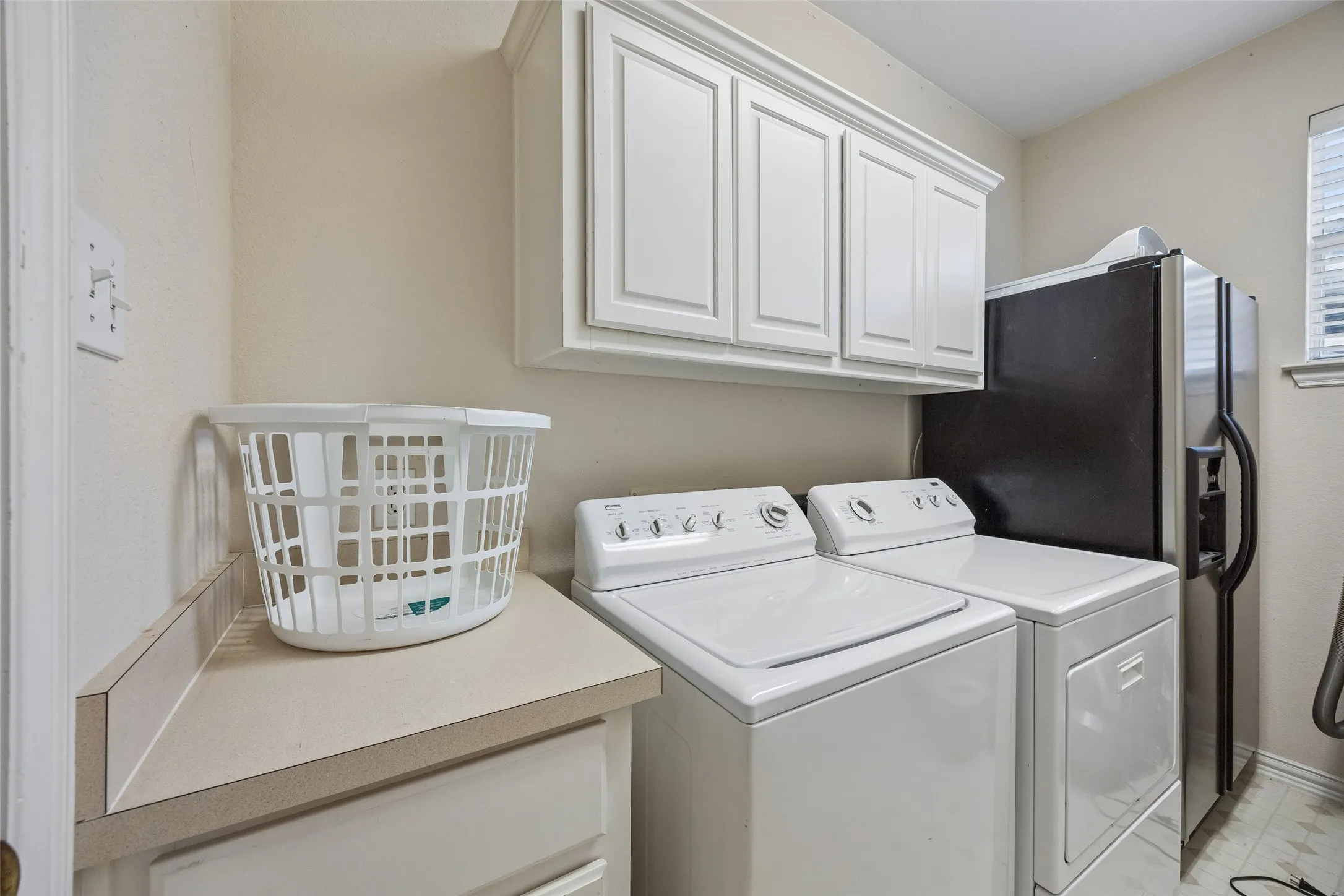 Utility area featuring upper cabinetry, a light-toned countertop, and a window