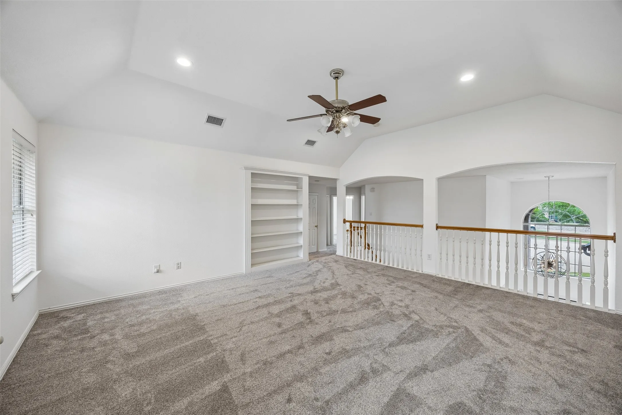 Spacious upper-level room featuring vaulted ceilings and recessed lighting