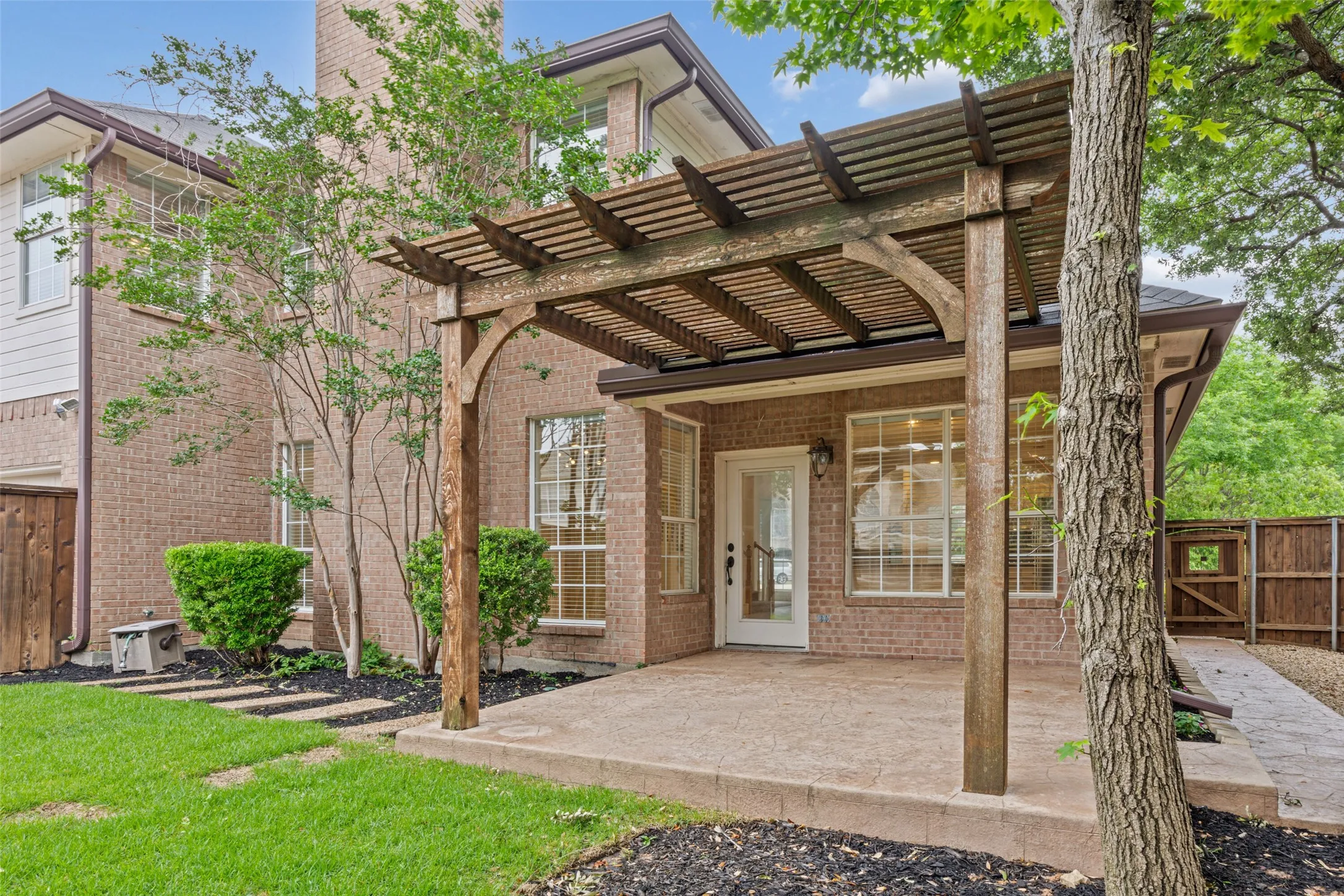 Brick exterior featuring a wood pergola over a concrete patio