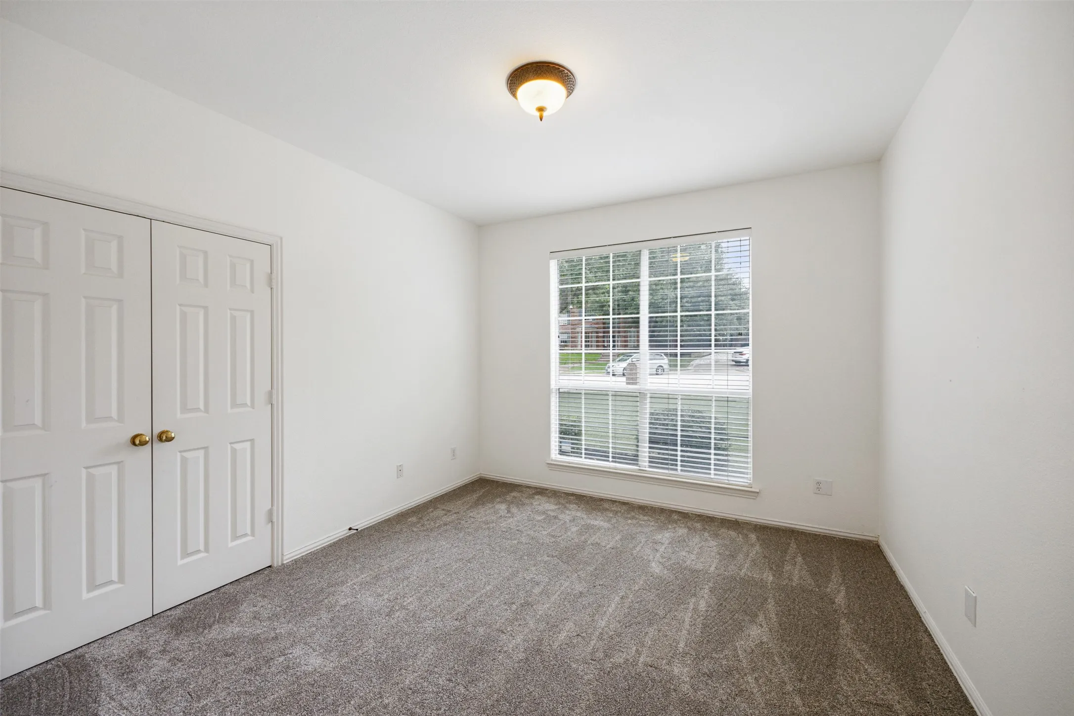 Bright interior space featuring a large window , neutral carpeting, and a double-door closet