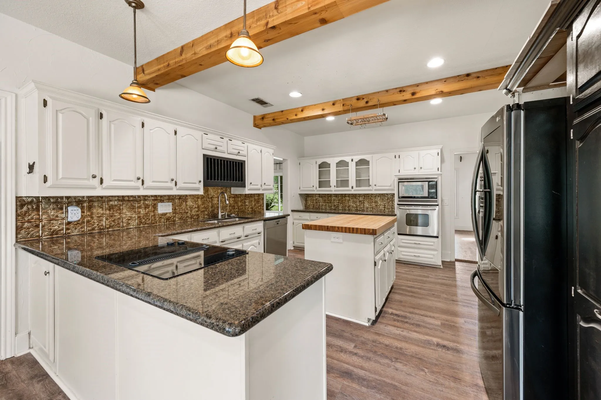 Beautiful beamed kitchen with down draft electric cooktop and tons of granite counter space